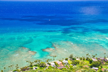 Looking down on the shoreline of Hawaii on a bright, sunny day with lots of blue ocean and reefs.