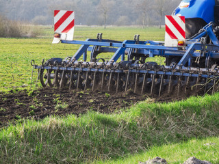 Blue tractor with cultivator in action