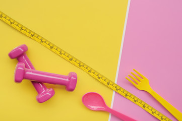 close up of spoon in tape measure with dumbbell for background