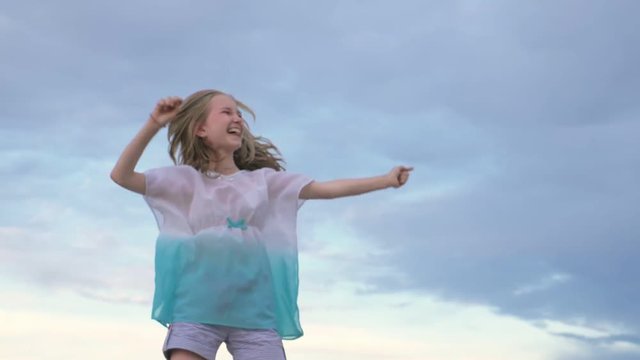 Two children dance and indulge on the beach. Children perform dancing stunts tricks. Hair fluttering in the wind. The kid spin and jump, shake their heads. One girl is a teenager.