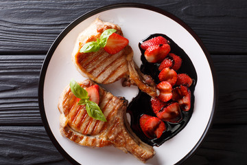 Hot grilled tasty pork chop with balsamic strawberry close-up on a plate. horizontal top view