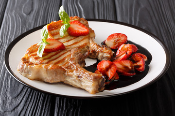 Meat and berries: grilled pork chop with basil and balsamic strawberry sauce close-up on a plate. horizontal