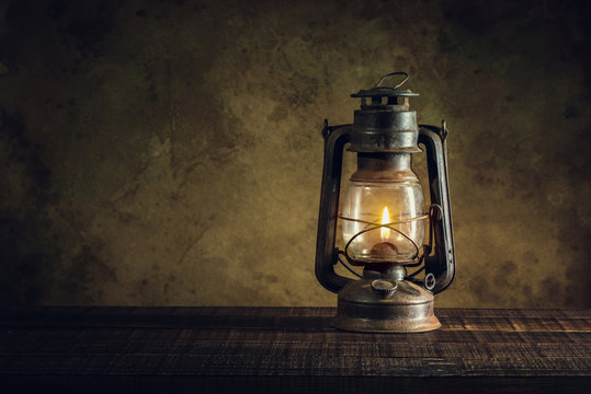 Vintage old lantern lighting in the dark forest. Travel camping concept.  Burning lantern on a moss at forest in the night. Stock Photo