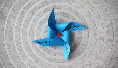 A blue pinwheel with '#PayMeToo' on it. #PayMeToo as social new movement.