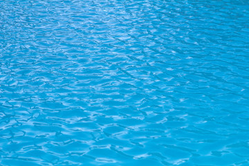 Fototapeta na wymiar small waves and ripples on the blue water of the swimming pool