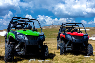 Parked ATV and UTV, buggies on mountain peak with clouds and blue sky in background © FS-Stock