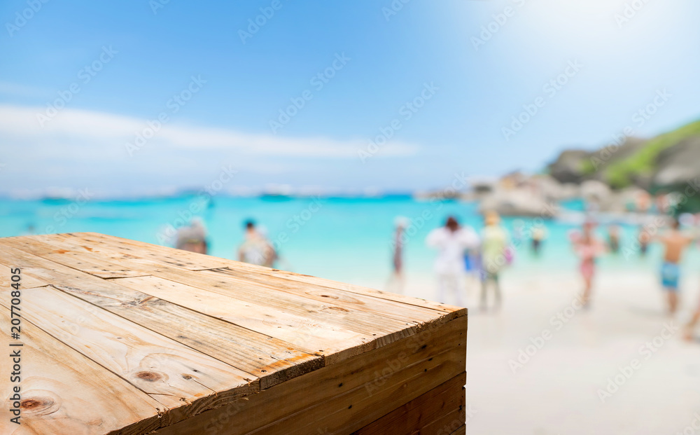 Aufkleber empty wood plank table food stand with blur tourist on sand beach for summer vacation with bokeh lig