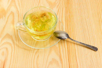Linden flower tea in transparent glass cup on wooden surface