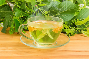 Linden tea in glass cup against of fresh linden branches