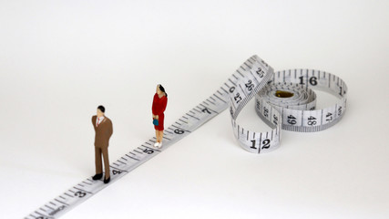 White tape measure with miniature people. The gender gap concept in employment and promotion.