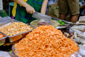 Sellers are using a large knife cut organic fish, using a preservative method by drying salty. To keep from spoiling food.