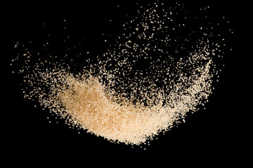 Brown sugar flying explosion splash isolated on black background  ,throwing freeze stop motion...