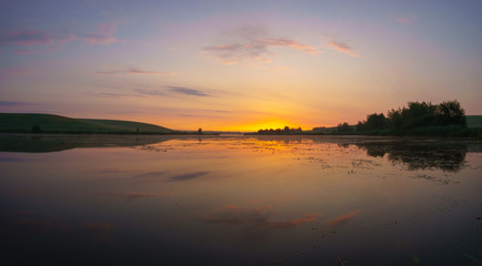 Obraz premium sunrise over a lake surrounded by meadows and fields