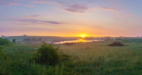Fototapeta na wymiar sunrise over a lake surrounded by meadows and fields
