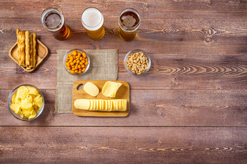 glasses of light and dark beer with assorted snacks on a wooden table background with copy space for text. bachelor party, pub, bar or degustation concept. top view, flat lay
