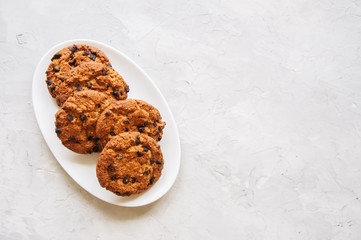 Homemade chocolate chip cookies in a plate on a white stone background. Top view and copy space.