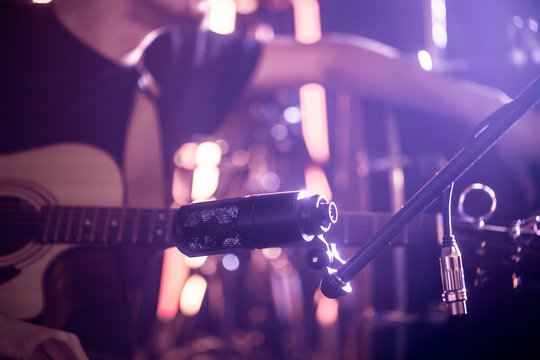 The musician connects the microphone to record an acoustic guitar close-up, in a recording Studio or concert hall.