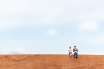 Business people sitting on wooden floor with blue sky background