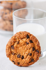 Homemade chocolate chip cookies and glass of fresh milk on a white stone background. Close up.