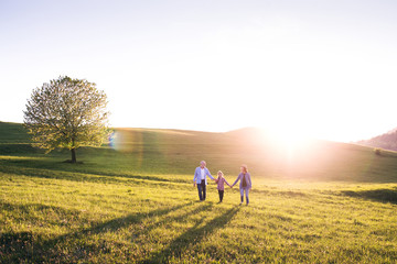 Senior couple with granddaughter outside in spring nature.