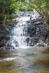Naklejka na ściany i meble Waterfall and clear stream in the green forest