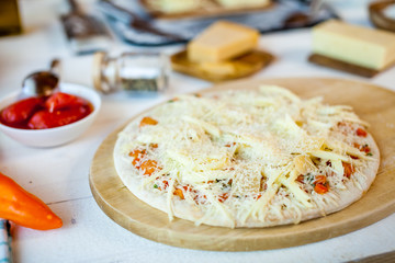 closeup raw fresh homemade traditional italian cheese pizza ready to cook on wooden cooking table with ingredients. wallpaper for pizzeria and food concept
