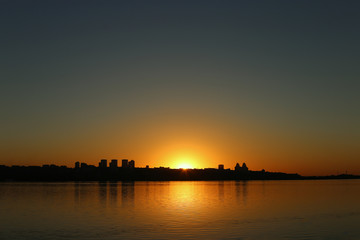 Beautiful sunset over the river with a view of the city, on the horizon.