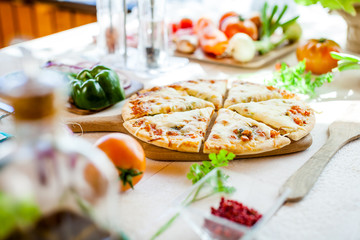 closeup fresh homemade traditional cheese italian pizza on wooden table with ingredients around. wallpaper for pizzeria and cooking food concept