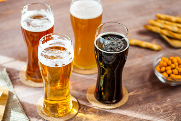 glasses of light and dark beer with assorted snacks on a wooden table background. bachelor party, pub, bar or degustation concept