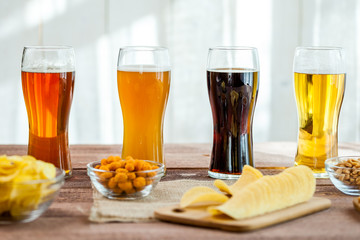 glasses of light and dark beer with assorted snacks on a wooden table background. bachelor party,...