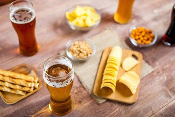 glasses of light and dark beer with assorted snacks on a wooden table background. bachelor party, pub, bar or degustation concept
