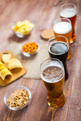 glasses of light and dark beer with assorted snacks on a wooden table background. bachelor party, pub, bar or degustation concept