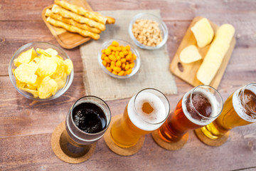 glasses of light and dark beer with assorted snacks on a wooden table background. bachelor party, pub, bar or degustation concept