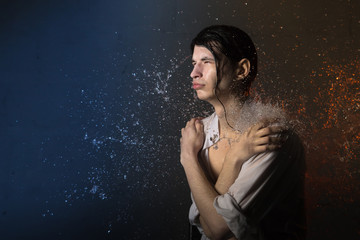 Portrait of attractive young man brunette in wet clothes and splashes of water. Studio photo