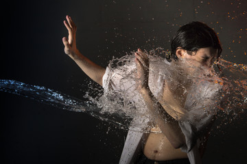Portrait of attractive young man brunette in wet clothes and splashes of water. Studio photo