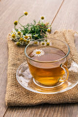 Glass cup of green tea with white chamomile flowers