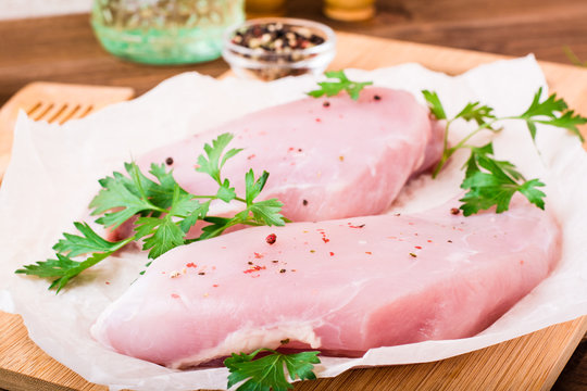 Raw turkey fillet in spices and herbs on a cutting board on a wooden table