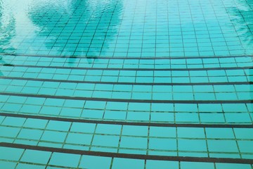 The swimming pool with way down and reflection of the coconut trees. Soft focus. Sport and background concept.