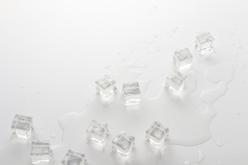 Cubes of ice and spilled water on a light background