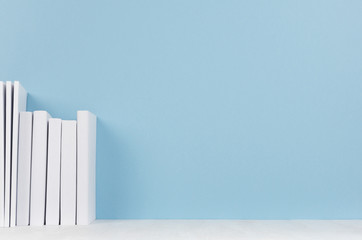 Row of white books on light wood desk  and soft pastel blue background with copy space. Home decor.