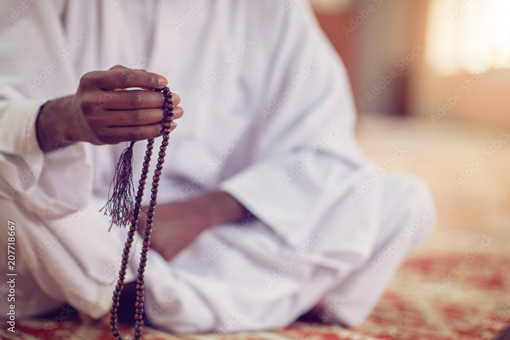 Poster african muslim man making traditional prayer to god while wearing dishdasha