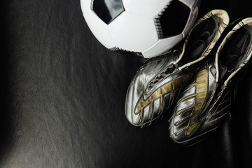 Flat lay soccer football accessories on a dark leather background. Mock-up with copy space for text.
