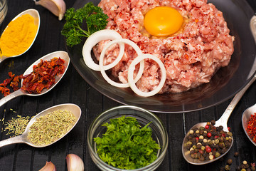 Minced meat. Ground meat with ingredients for cooking on a black background.
