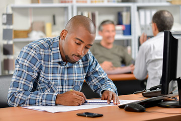 Man sat at desk working on blueprints