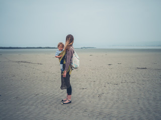 Young mother on beach with child in sling