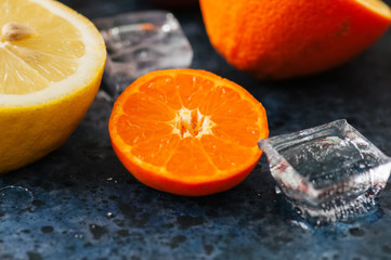Fototapeta na wymiar Mix of fresh ripe citrus fruits as blood oranges, mandarines, lemons with ice cubes on a blue stone background. Top view.