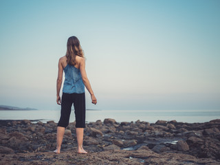 Young woman standing on coast at sunset