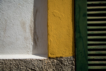  The brick wall is white and yellow. Wooden shutters are green.