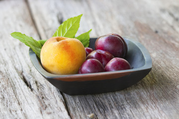 plums and peaches on wooden basket