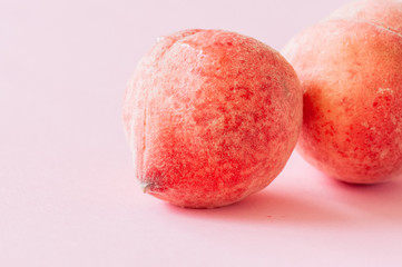 Two fresh ripe peaches on a pink background. Organic food concept. Close up.